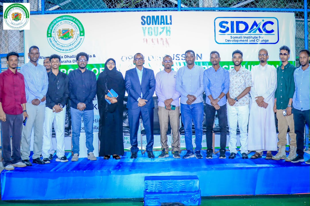 A group of participants standing together on a blue stage in front of the SIDAC discussion banner